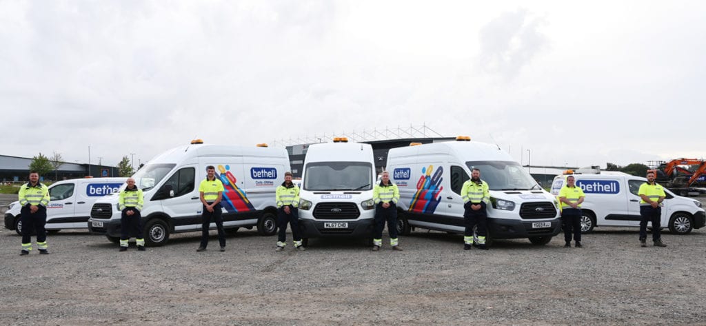 Line-up of Bethell utility operatives side by side next to Bethell vans