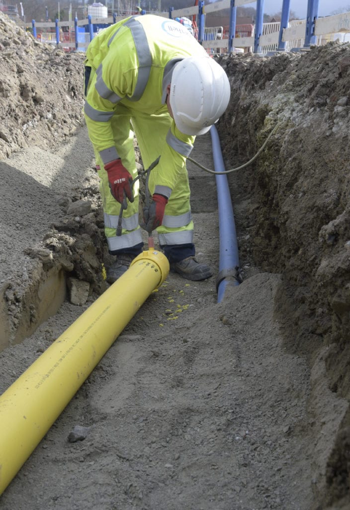 Utility operative installing a gas pipe in a trench