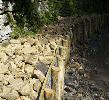 Barrier installed at the side of a river bed