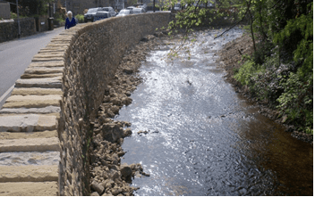 Wall dividing a river and a public road
