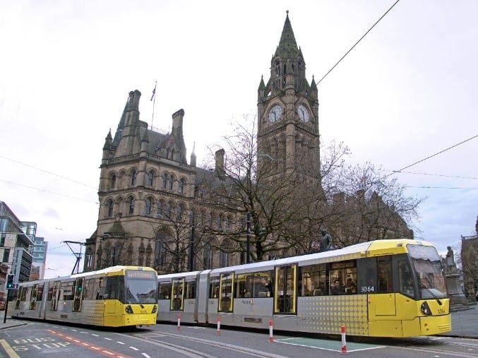 Two Metrolink trams in front of a cathedral