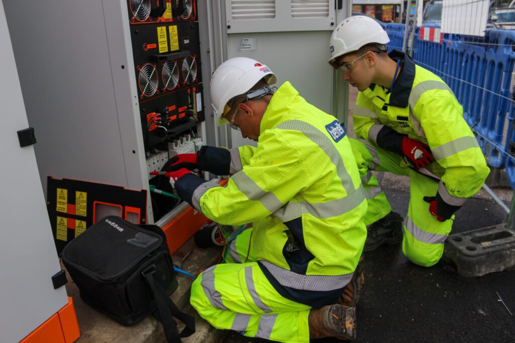 Two utility operatives installing a substation for an electric vehicle charging hub
