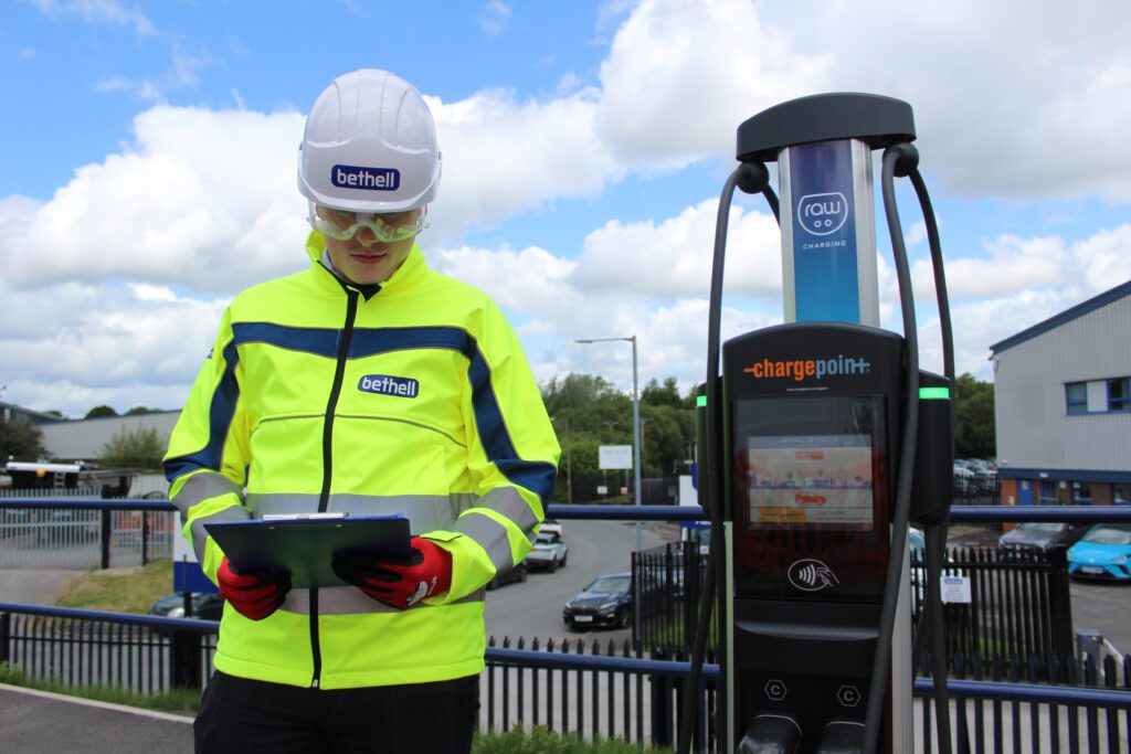 A Bethell operative next to an electric vehicle charger at Bethell's head office