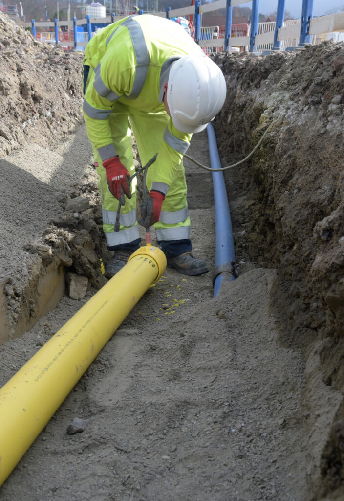 Utility operative installing gas main in a trench