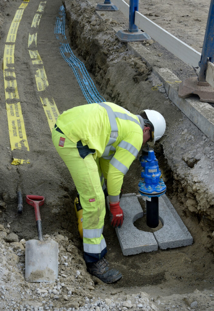 Utility operative installing water main in a trench